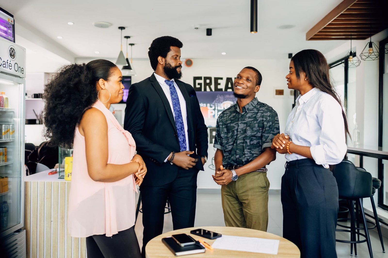 Team of Nigerian professionals in a relaxed standing meeting in a modern Lagos office